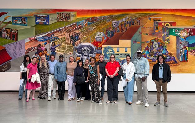 Representatives from Bay Area arts organizations photographed together in front of a mural on a coalition-building trip.