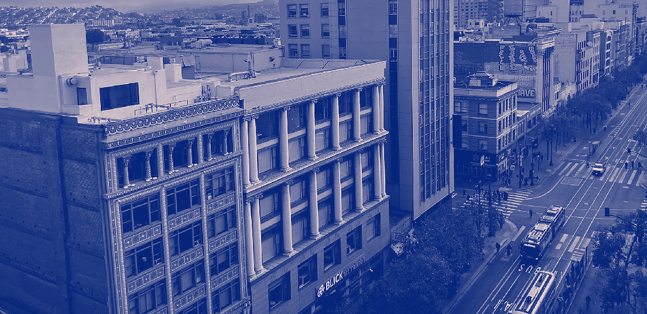 Market Street from above: the old commercial blocks of Mid-Market, streetcars on the tracks below.