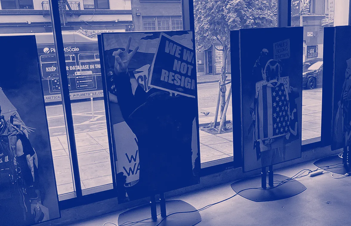 Protest placards painted on tall panels, standing in a gallery's street windows.